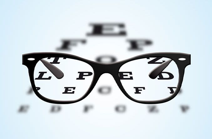 Black framed spectacles and an eye chart
