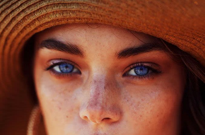 Woman wearing hat with blue eyes.