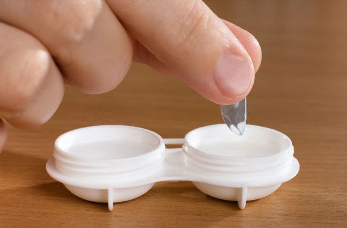 Person removing contact lens from protective case