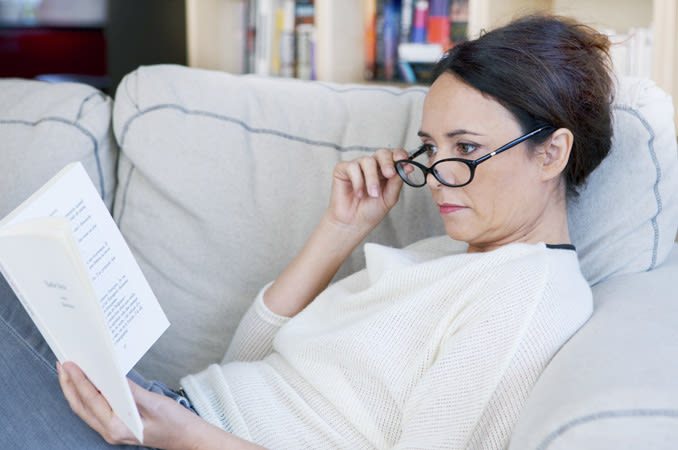 Woman with eye glasses reading a book